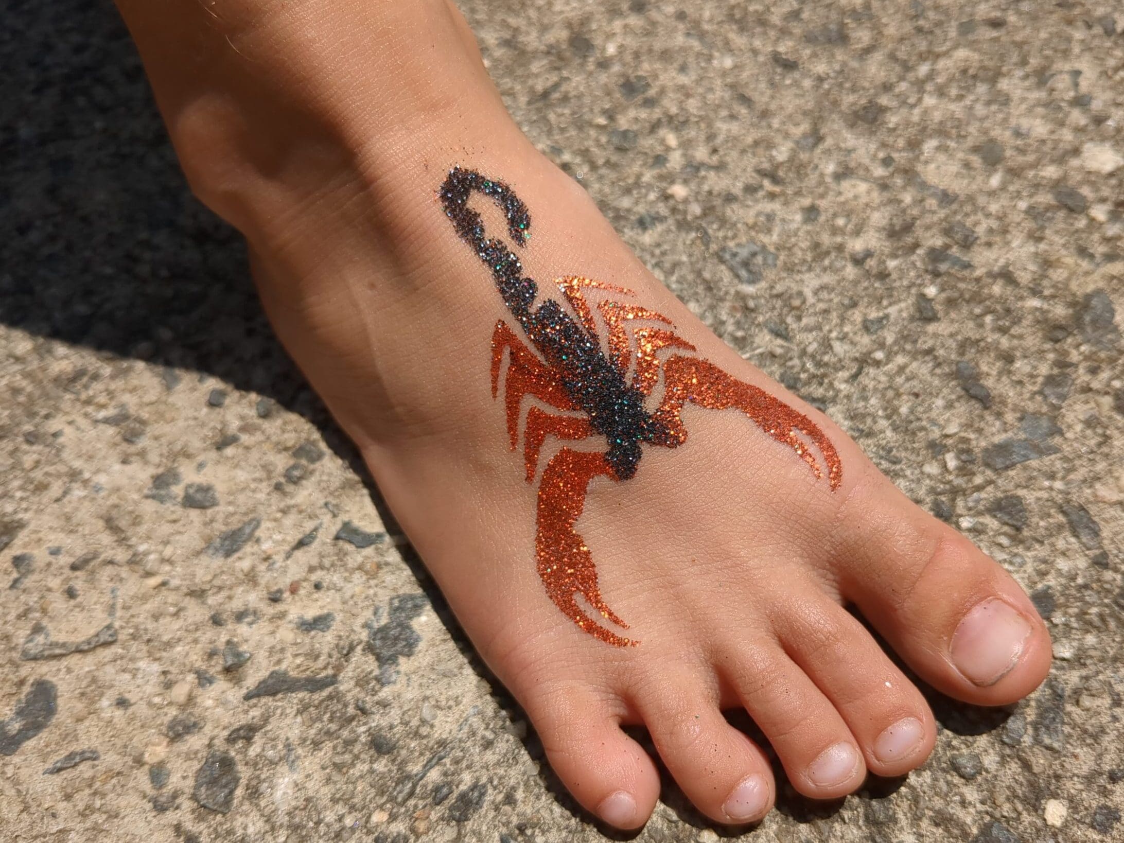 Scorpion Glitter Tattoo - Made Ya Look Foam Party black and orange scorpion glitter tattoo on a foot at a pool party