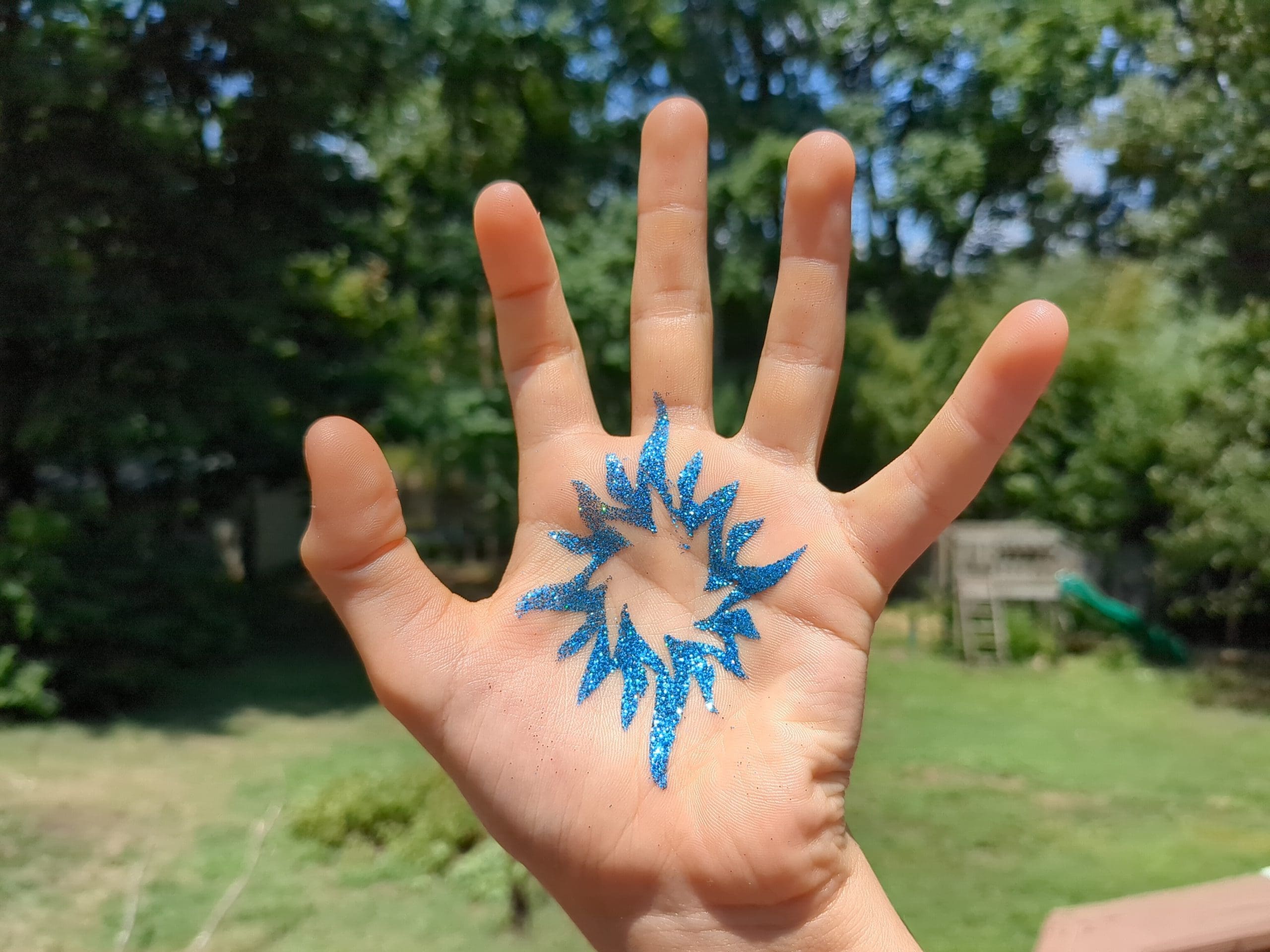 Sunburst Glitter Tattoo - Made Ya Look Foam Party picture of a blue sunburst glitter tattoo on the palm of a hand
